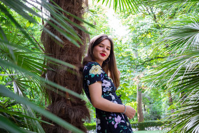 Portrait of smiling woman standing against trees