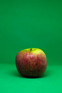 Close-up of apple on table against green background