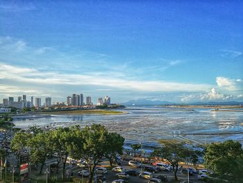 Scenic view of sea by city buildings against blue sky