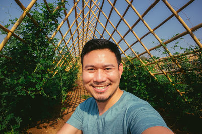 Portrait of smiling man standing in greenhouse