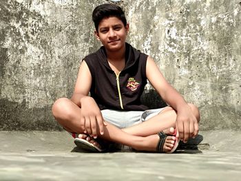 Portrait of boy sitting against wall