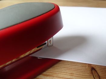 Close-up of paper amidst red stapler on table