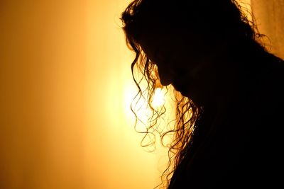 Close-up portrait of silhouette woman against orange sky