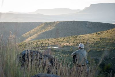 Rear view of man on field against mountain range