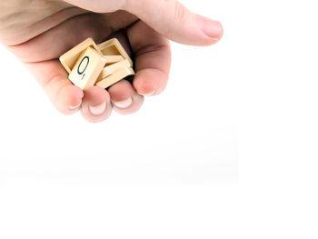 Cropped image of hand holding paper over white background