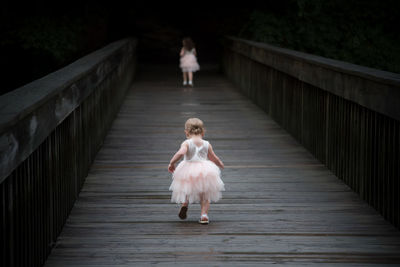 Rear view of women walking on footbridge