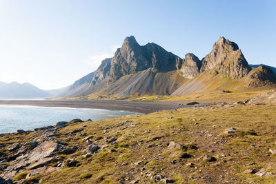 Scenic view of sea and mountains against clear sky