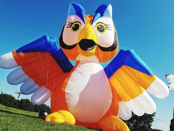 Inflatable kite on grassy field against clear sky