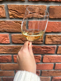 Close-up of hand holding glass against wall