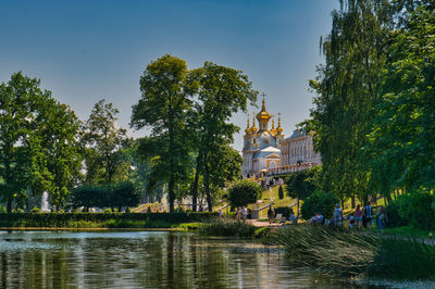 Scenic view of lake by trees and buildings against sky