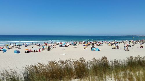 People on beach against clear blue sky