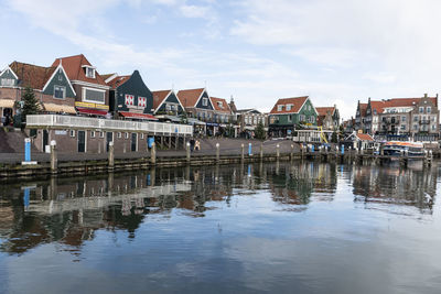 Buildings by river against sky