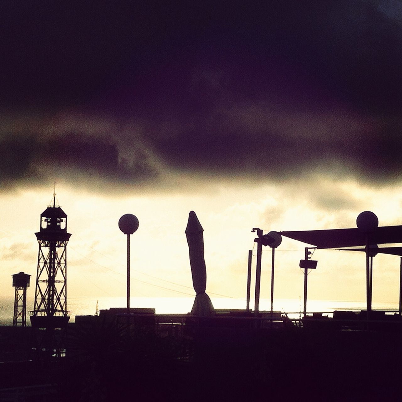 silhouette, sky, cloud - sky, low angle view, cloudy, built structure, architecture, dusk, building exterior, sunset, weather, cloud, industry, overcast, dramatic sky, outdoors, street light, lighting equipment, city, outline