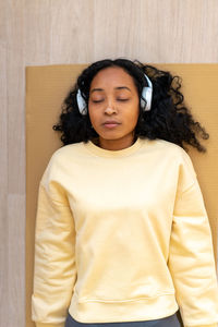 African-american female in headphones lying on mat with closed eyes. relaxing after workout