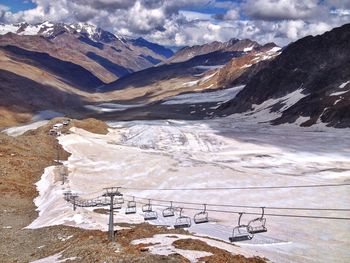 Scenic view of snowcapped mountains and overhead cable car against sky