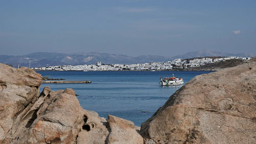 People on boat in sea against mountains in city