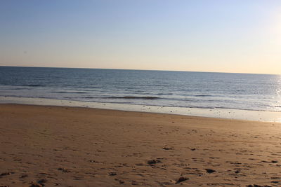 Scenic view of beach against clear sky during sunset