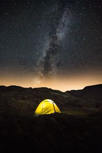 Yellow tent with a sky full of stars and the milky way 