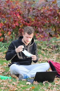 Young man looking away while sitting on land