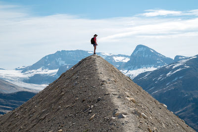 Low angle view of person standing on mountain against sky