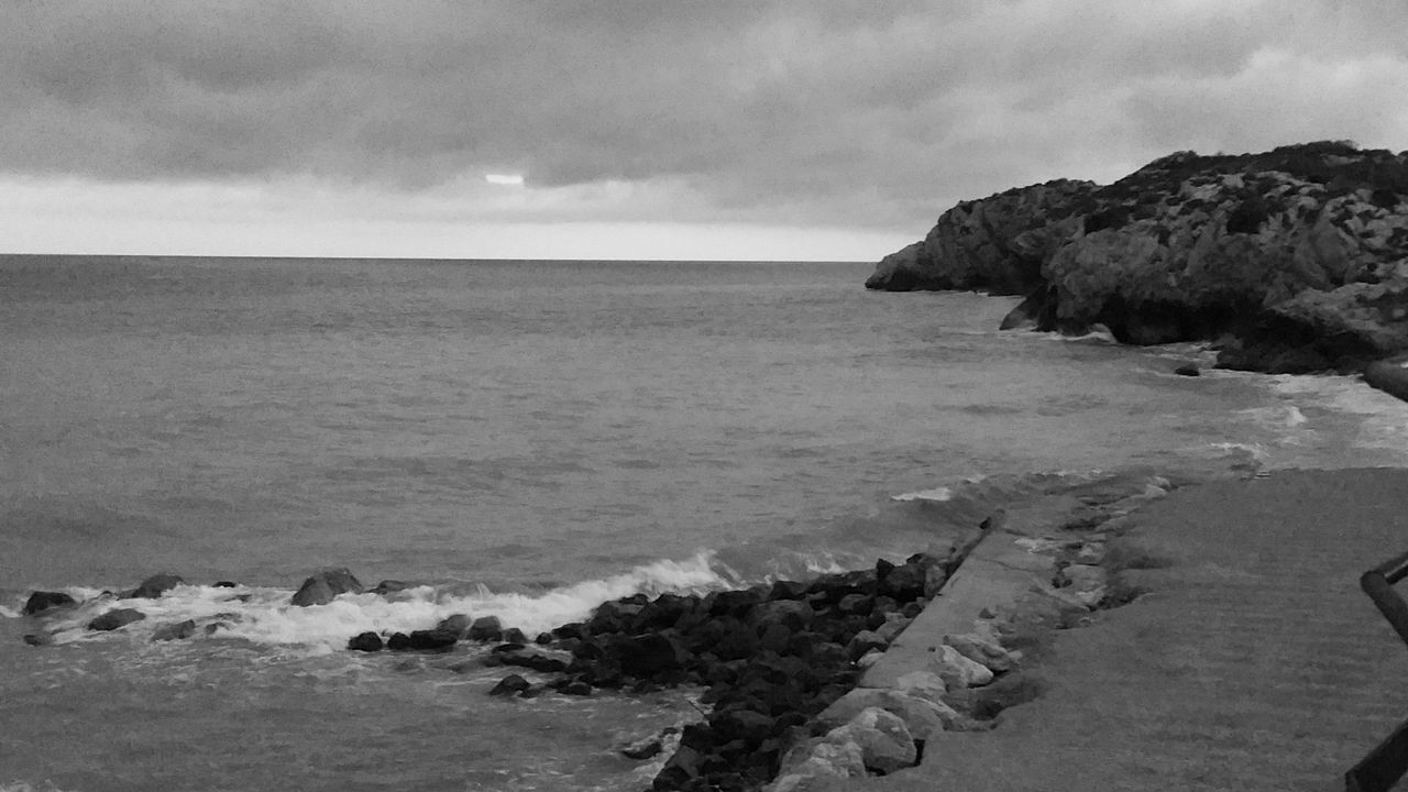 sea, water, land, beach, sky, black and white, coast, rock, cloud, scenics - nature, ocean, beauty in nature, shore, monochrome photography, nature, monochrome, wave, horizon, horizon over water, tranquility, environment, coastline, tranquil scene, no people, wind wave, travel destinations, outdoors, bay, day, body of water, terrain, seascape, travel, sand, landscape, rock formation, cliff, non-urban scene, tourism, idyllic, cove