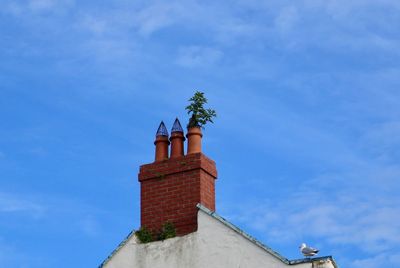 Low angle view of cross on roof of building against sky