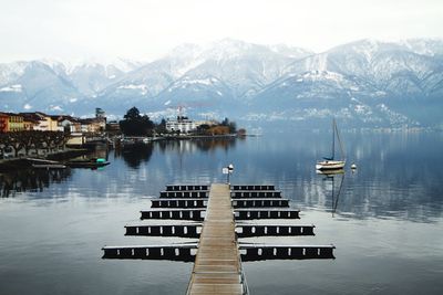 Pier amidst lake against snowcapped mountains