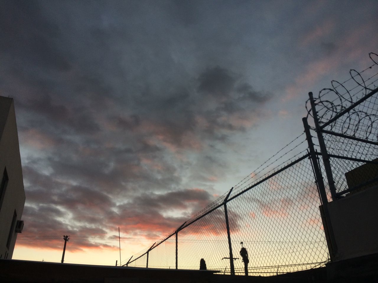 sky, silhouette, low angle view, built structure, cloud - sky, lifestyles, leisure activity, men, architecture, sunset, cloudy, person, building exterior, cloud, outdoors, dusk, unrecognizable person