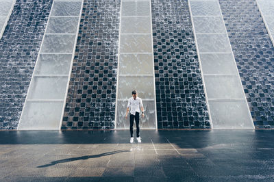 Young man looking down standing against wall