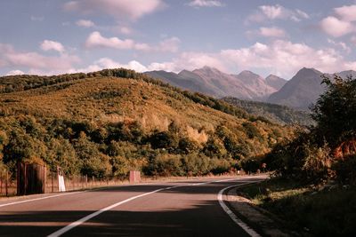 Road leading towards mountains against sky