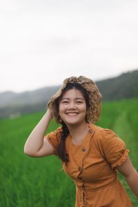 Portrait of smiling young woman standing on field