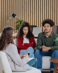 Portrait of smiling friends sitting on sofa at home