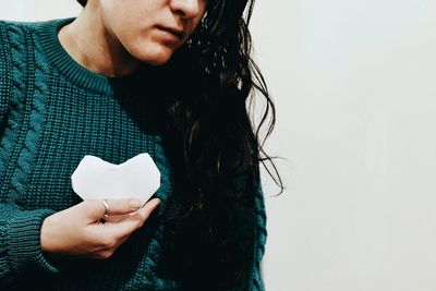 Close-up of woman holding hands over white background