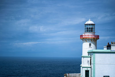 Lighthouse by sea against sky