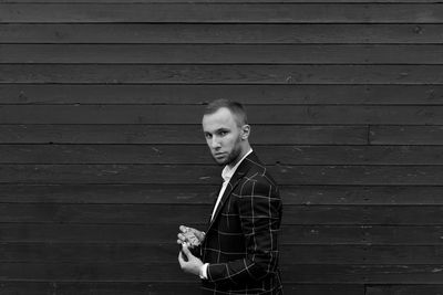Portrait of young man standing against wall