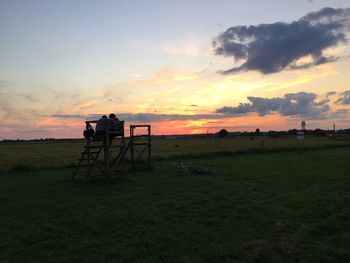 Silhouette cart on field against sky during sunset