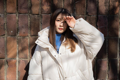 Young woman standing against wall