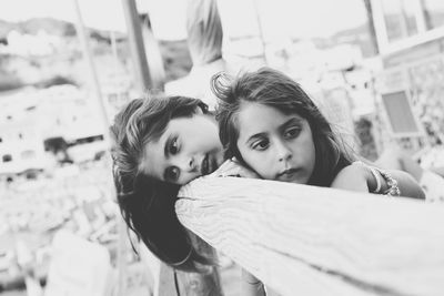 Thoughtful sisters leaning on wooden railing