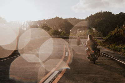 Two women on motor scooters on country road, siargao island, philippines