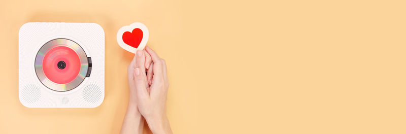 High angle view of hand holding in-ear headphones against pink background