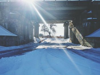 Sunlight streaming through snow covered house against sky