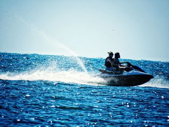 Man riding boat on sea against clear sky