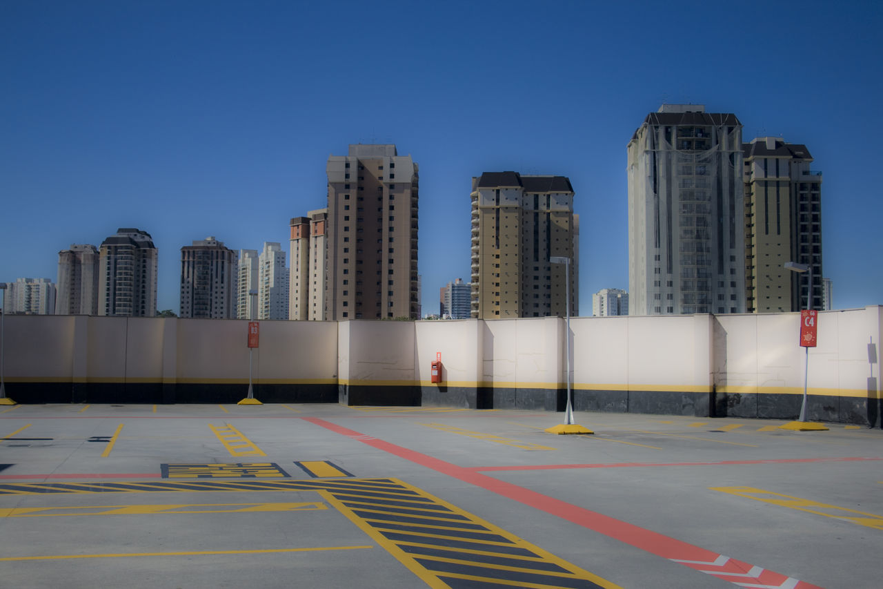 building exterior, clear sky, architecture, built structure, city, copy space, blue, modern, skyscraper, building, office building, road, day, outdoors, street, sunlight, tower, empty, tall - high, city life