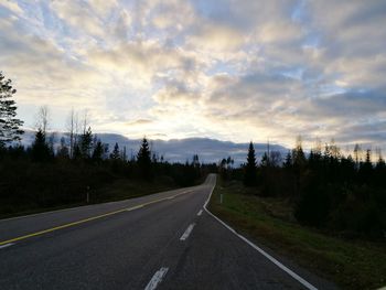 Country road against cloudy sky