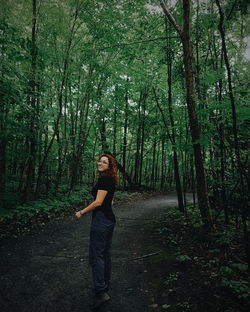 Full length of young woman standing in forest