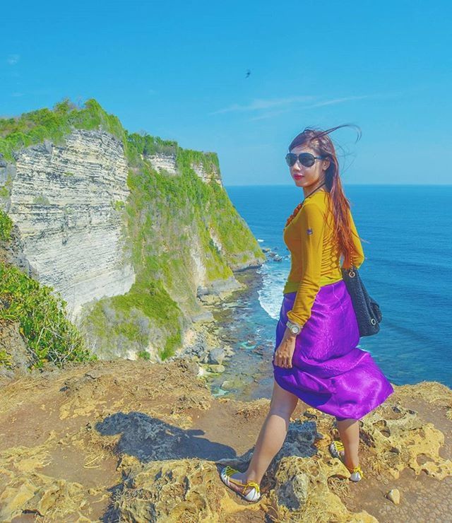 sea, lifestyles, casual clothing, water, leisure activity, full length, standing, beach, person, young adult, horizon over water, shore, vacations, sky, rock - object, young women, sunlight, blue