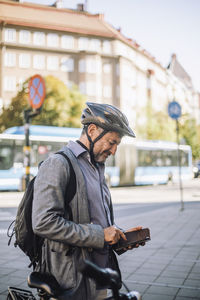 Mature businessman using smart phone standing at street