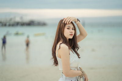 Young woman standing at beach against sky