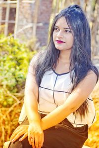 Thoughtful beautiful young woman sitting outdoors