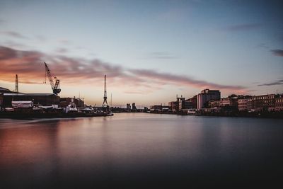 Harbor in city against blue sky during sunset